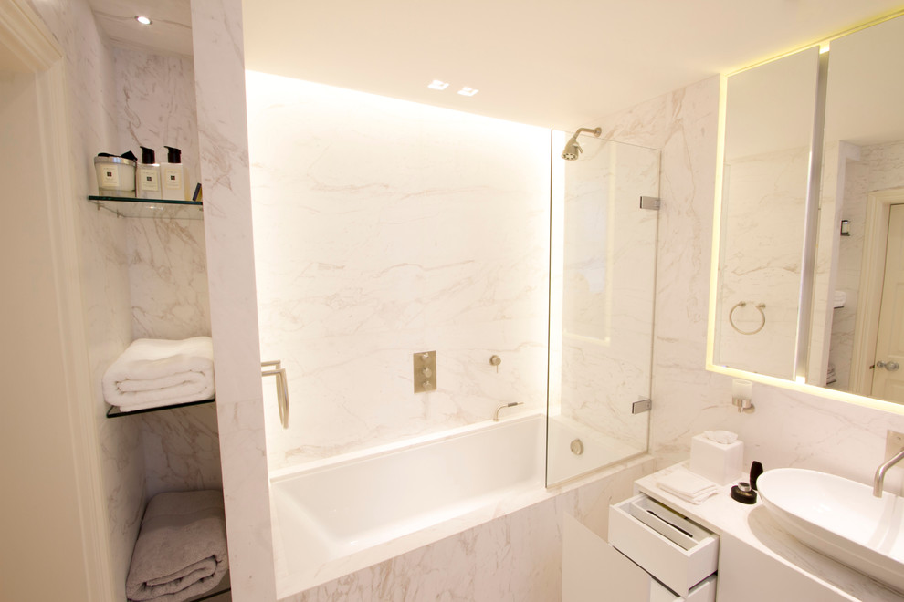 Photo of a medium sized modern ensuite bathroom in London with a built-in bath, a shower/bath combination, white tiles, stone slabs, white walls, marble flooring and marble worktops.