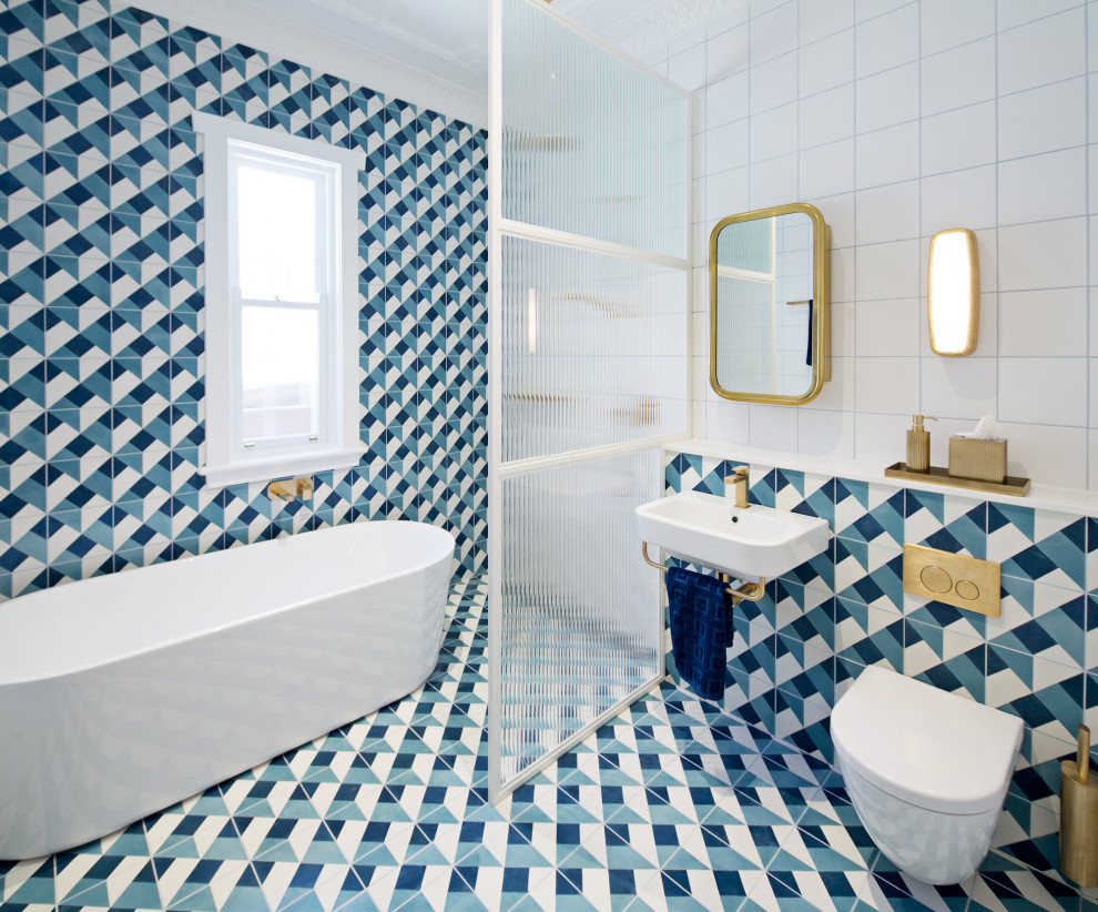 Modernes Badezimmer mit freistehender Badewanne, Wandtoilette, blauen Fliesen, Aufsatzwaschbecken und buntem Boden in Sydney