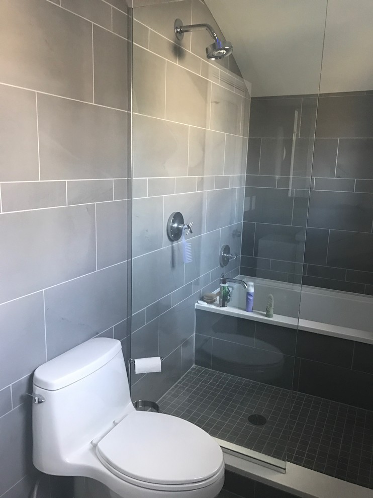 Modern inredning av ett badrum, med en hörndusch, en toalettstol med separat cisternkåpa, beige kakel, keramikplattor och grå väggar
