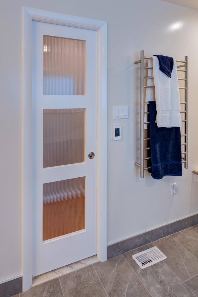 Modern inredning av ett mellanstort vit vitt en-suite badrum, med släta luckor, blå skåp, ett fristående badkar, en dusch/badkar-kombination, en toalettstol med hel cisternkåpa, grå kakel, porslinskakel, grå väggar, klinkergolv i porslin, ett undermonterad handfat, bänkskiva i kvarts, grått golv och med dusch som är öppen