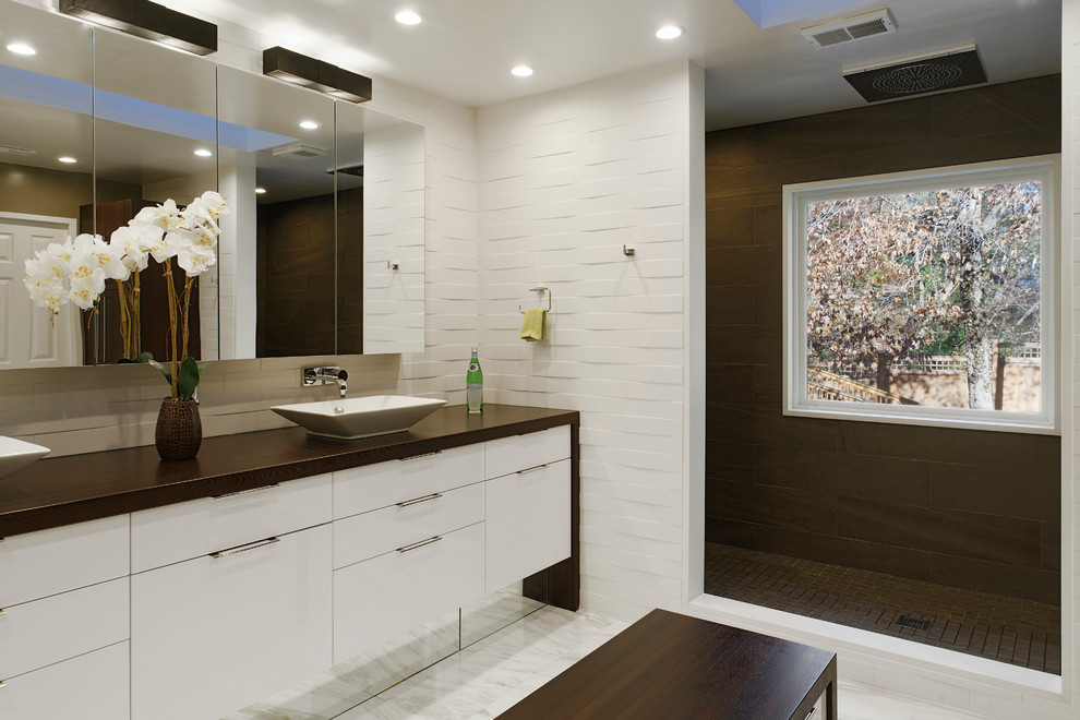 Пример оригинального дизайна: большая главная ванная комната в современном стиле с плоскими фасадами, белыми фасадами, открытым душем, унитазом-моноблоком, белой плиткой, каменной плиткой, белыми стенами, мраморным полом, настольной раковиной и столешницей из дерева