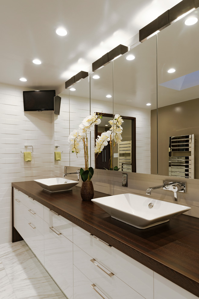 Inspiration for a large contemporary ensuite bathroom in DC Metro with flat-panel cabinets, white cabinets, white tiles, stone tiles, wooden worktops, a walk-in shower, a vessel sink, a one-piece toilet, white walls and marble flooring.
