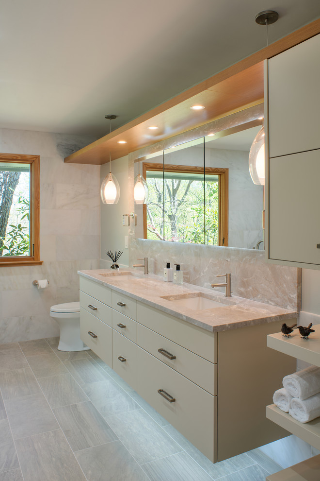 Design ideas for a large contemporary ensuite bathroom in DC Metro with flat-panel cabinets, beige cabinets, a freestanding bath, a shower/bath combination, beige tiles, marble tiles, beige walls, lino flooring, a submerged sink, marble worktops, beige floors, a hinged door, beige worktops and a one-piece toilet.