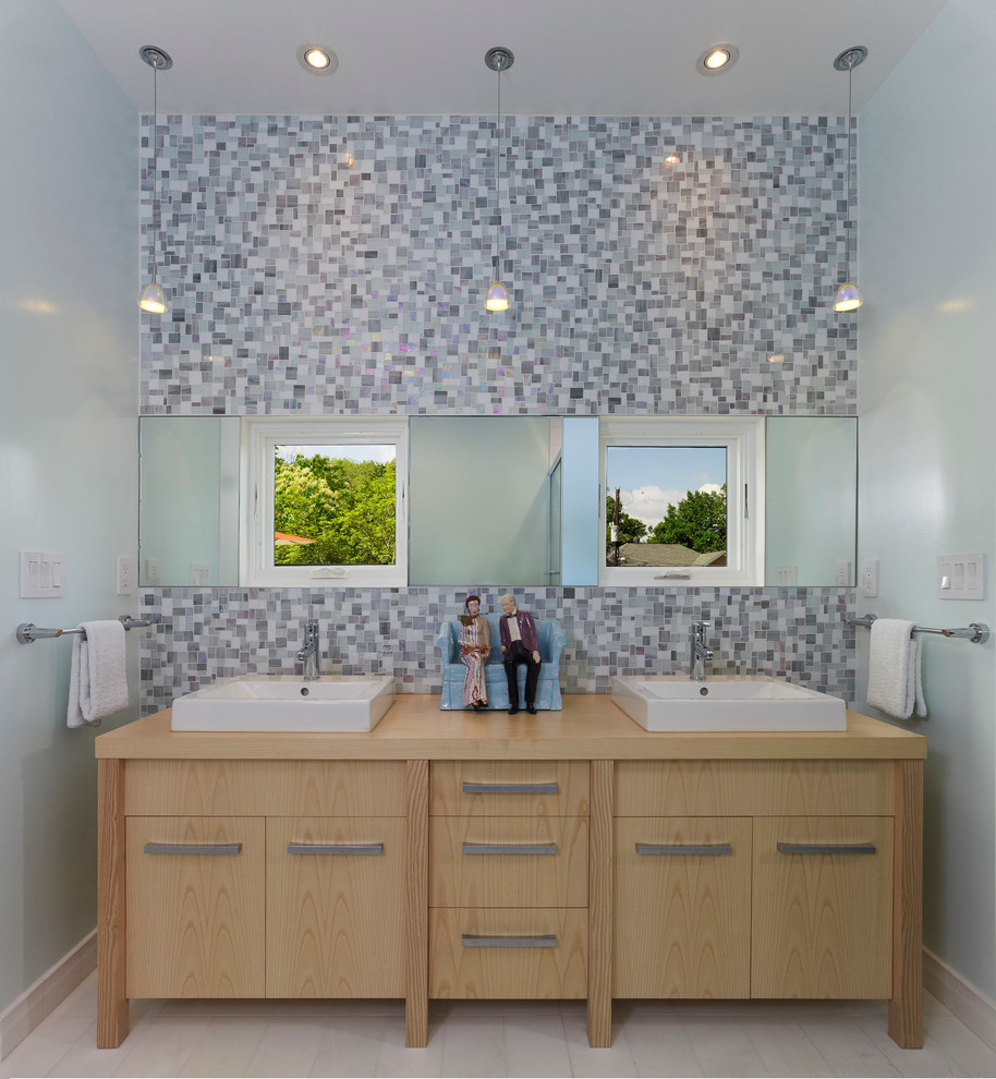 Modernes Badezimmer mit Aufsatzwaschbecken, verzierten Schränken, hellen Holzschränken, Waschtisch aus Holz und grauen Fliesen in Washington, D.C.