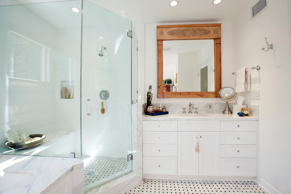 На фото: большая главная ванная комната в современном стиле с фасадами в стиле шейкер, белыми фасадами, ванной в нише, угловым душем, белой плиткой, белыми стенами, полом из мозаичной плитки, врезной раковиной и мраморной столешницей