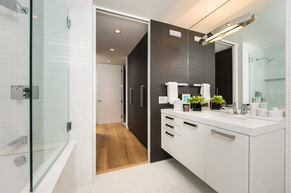 Exemple d'une salle d'eau tendance de taille moyenne avec un placard à porte plane, des portes de placard blanches, une baignoire en alcôve, un combiné douche/baignoire, un carrelage blanc, un lavabo encastré, un sol blanc, un plan de toilette blanc et un sol en terrazzo.
