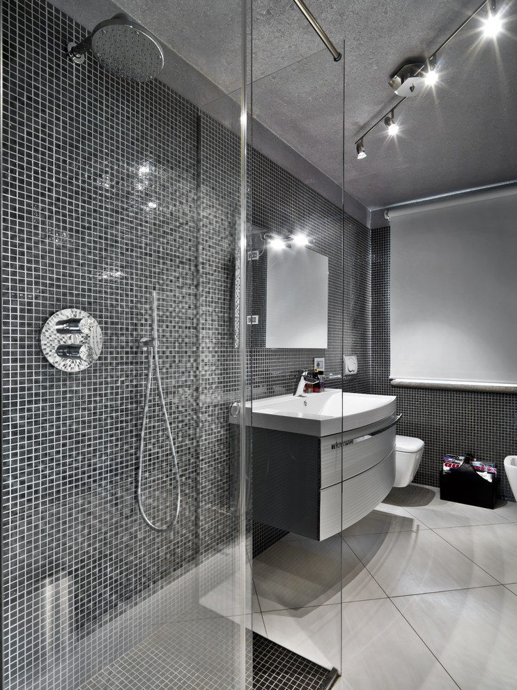Photo of a large contemporary shower room bathroom in Los Angeles with a wall-mounted sink, flat-panel cabinets, distressed cabinets, a corner shower, black tiles, mosaic tiles, solid surface worktops, a wall mounted toilet, black walls and lino flooring.