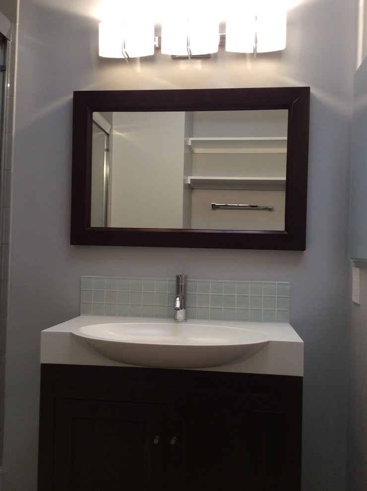 Example of a mid-sized trendy gray tile and porcelain tile medium tone wood floor bathroom design in Los Angeles with a console sink, shaker cabinets, dark wood cabinets, solid surface countertops, a one-piece toilet and gray walls