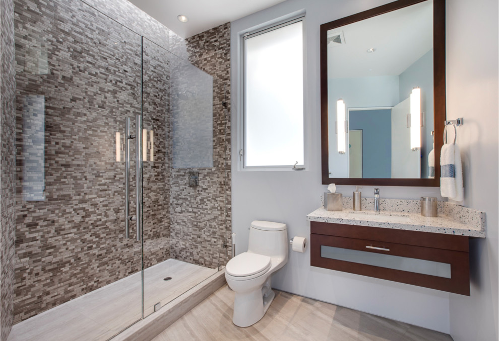 Bild på ett stort funkis badrum med dusch, med släta luckor, skåp i mörkt trä, en toalettstol med hel cisternkåpa, svart och vit kakel, keramikplattor, blå väggar, travertin golv, ett undermonterad handfat och bänkskiva i kalksten