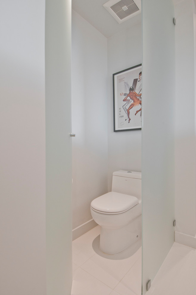 Cette photo montre un grand WC et toilettes moderne avec un placard à porte plane, des portes de placard marrons, un carrelage gris, du carrelage en pierre calcaire, un mur blanc, un sol en carrelage de porcelaine, un lavabo encastré et un sol beige.