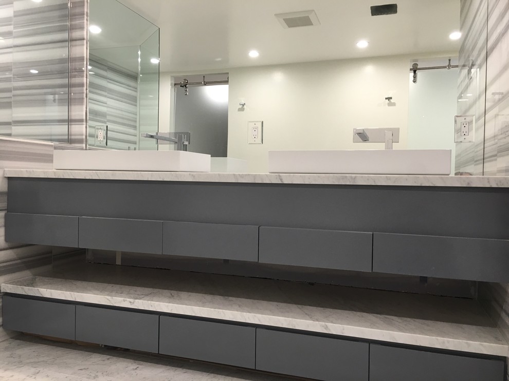 Idéer för mellanstora funkis en-suite badrum, med släta luckor, grå skåp, ett fristående badkar, en hörndusch, en toalettstol med hel cisternkåpa, vit kakel, stenkakel, vita väggar, marmorgolv, ett konsol handfat och marmorbänkskiva