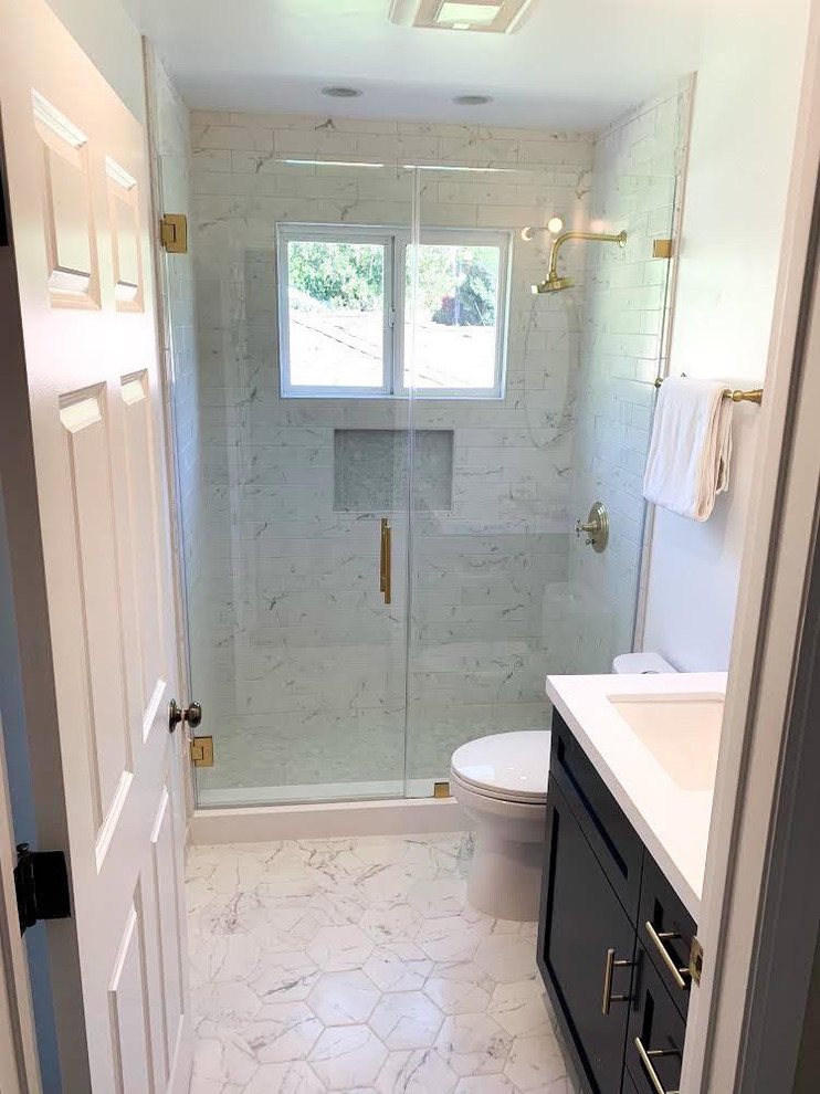 Inredning av ett modernt litet vit vitt badrum med dusch, med skåp i shakerstil, svarta skåp, en dusch i en alkov, en toalettstol med separat cisternkåpa, vit kakel, tunnelbanekakel, vita väggar, marmorgolv, ett undermonterad handfat, bänkskiva i akrylsten, vitt golv och dusch med gångjärnsdörr