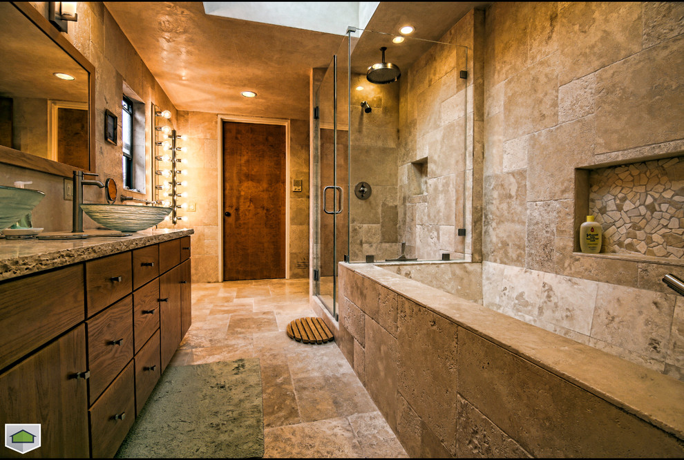 Cette photo montre une salle de bain chic avec une vasque, un placard à porte plane, des portes de placard marrons, WC suspendus, un carrelage beige et un carrelage de pierre.