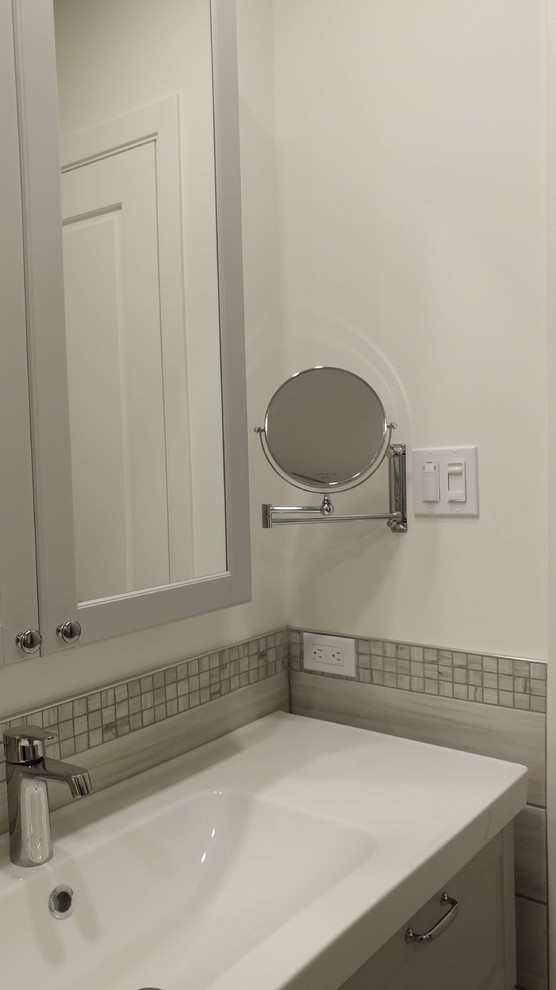 Cette image montre une petite salle de bain principale design avec un placard à porte shaker, des portes de placard grises, une baignoire en alcôve, un combiné douche/baignoire, WC à poser, un carrelage gris, des carreaux de porcelaine, un mur blanc, un sol en carrelage de porcelaine, un lavabo intégré, un sol gris, une cabine de douche à porte battante et un plan de toilette blanc.