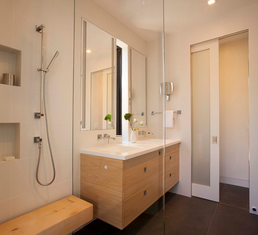 Example of a mid-sized master gray tile and ceramic tile ceramic tile walk-in shower design in San Francisco with flat-panel cabinets, light wood cabinets, white walls, an integrated sink and solid surface countertops