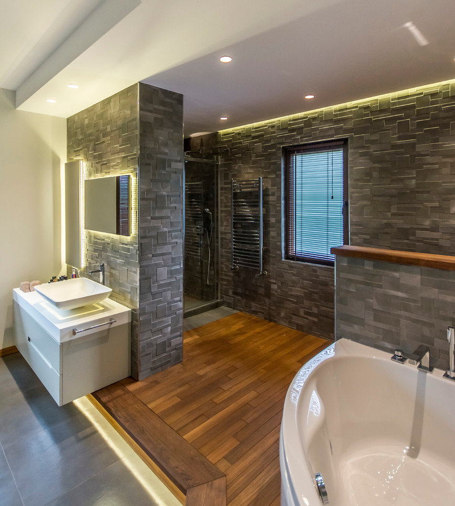 Immagine di una stanza da bagno minimal con lavabo a bacinella, ante lisce, piastrelle grigie, pareti beige, pavimento in legno massello medio, ante grigie e doccia alcova