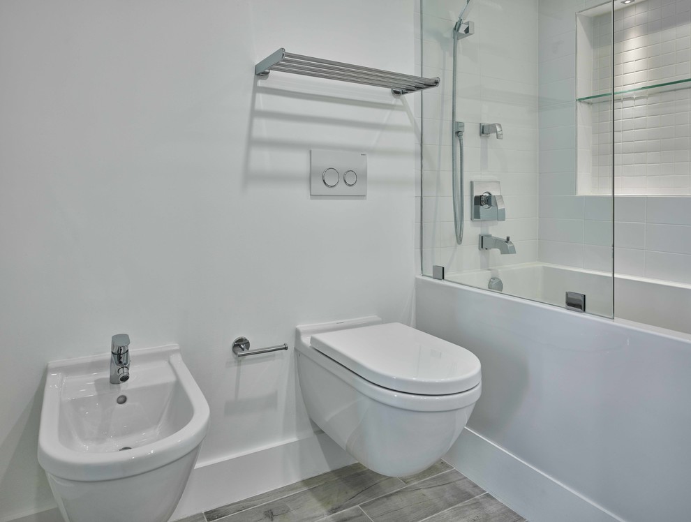 На фото: ванная комната в стиле модернизм с гидромассажной ванной, душем над ванной, инсталляцией, белой плиткой, плиткой кабанчик, белыми стенами, полом из керамогранита и подвесной раковиной с