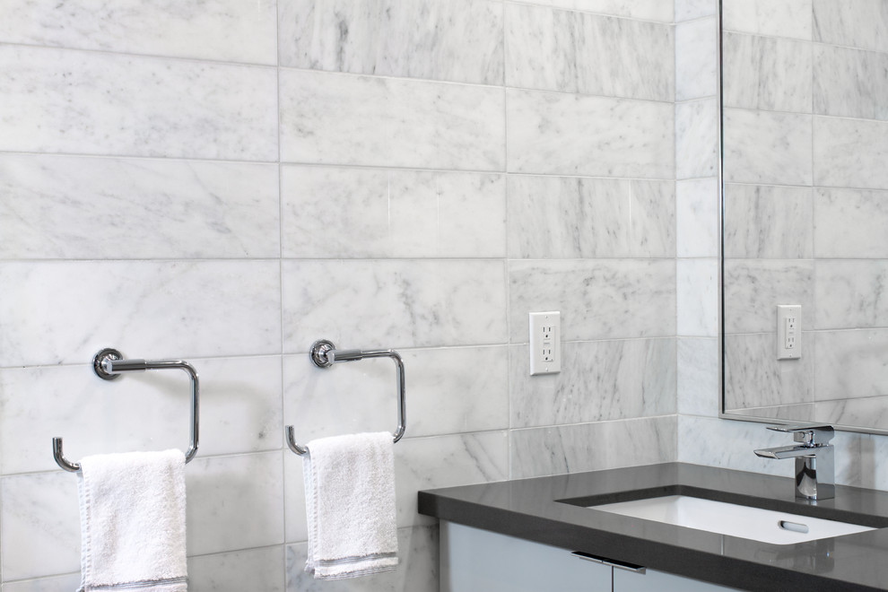 Immagine di una grande stanza da bagno padronale minimalista con lavabo sottopiano, ante lisce, ante bianche, piastrelle grigie, pareti bianche, piastrelle in pietra e pavimento in marmo