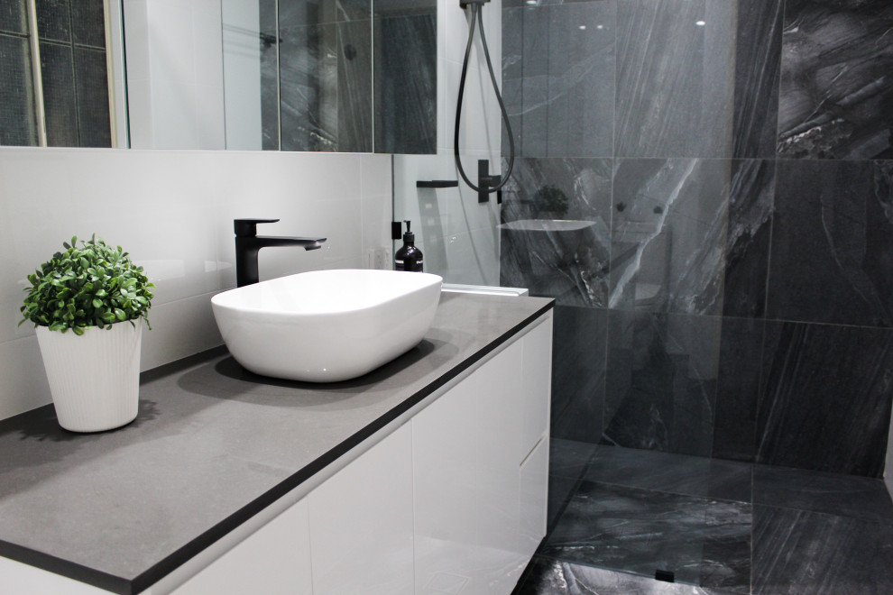 Example of a small minimalist master white tile and ceramic tile porcelain tile and gray floor bathroom design in Perth with flat-panel cabinets, white cabinets, a one-piece toilet, black walls, a vessel sink, quartz countertops and gray countertops