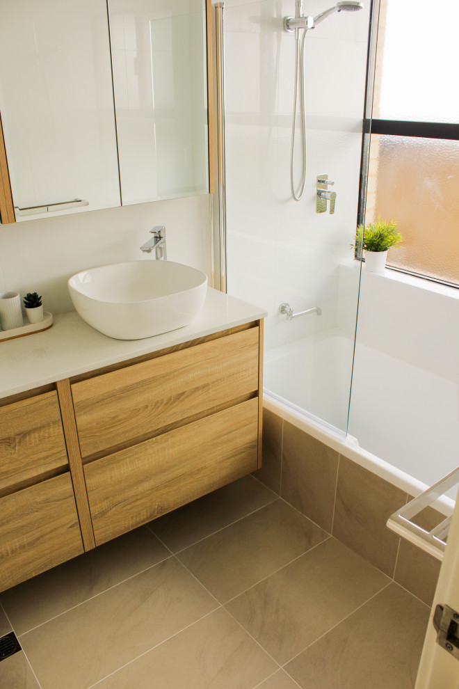 Стильный дизайн: ванная комната среднего размера в стиле модернизм с плоскими фасадами, бежевыми фасадами, накладной ванной, душем над ванной, унитазом-моноблоком, белой плиткой, керамической плиткой, белыми стенами, полом из керамогранита, душевой кабиной, настольной раковиной, столешницей из искусственного камня, бежевым полом, душем с распашными дверями и белой столешницей - последний тренд