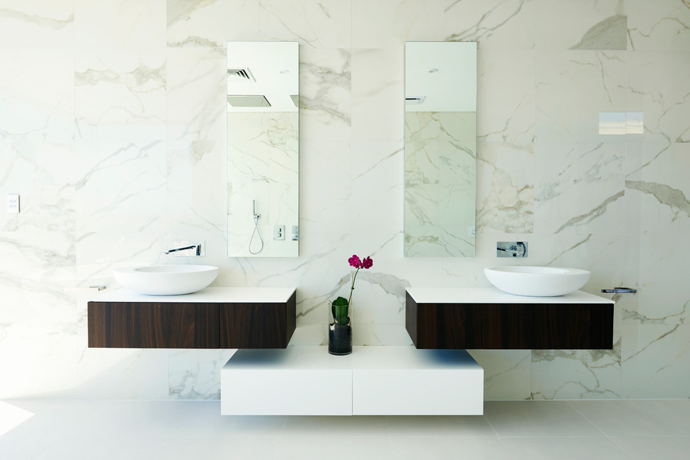 Idée de décoration pour une salle de bain design avec une vasque, un placard à porte plane et un carrelage de pierre.