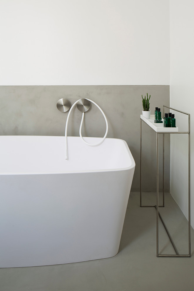 Freestanding bathtub - mid-sized contemporary master gray tile light wood floor and beige floor freestanding bathtub idea in London with flat-panel cabinets, white cabinets, a wall-mount toilet, white walls, an integrated sink and concrete countertops
