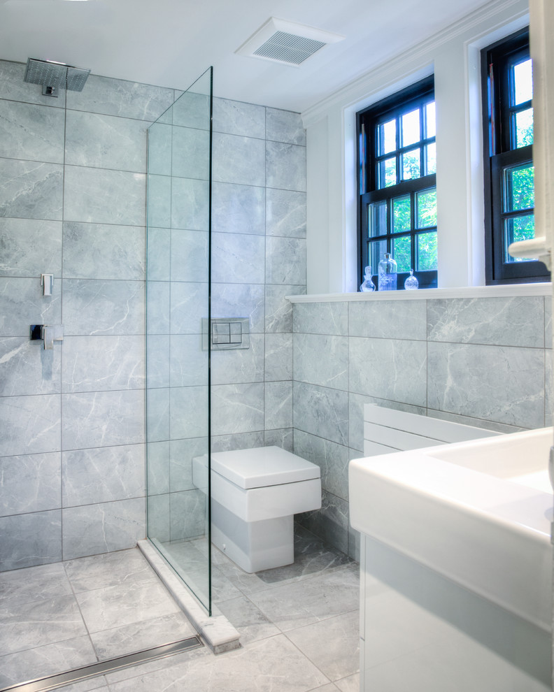Photo of a small modern ensuite bathroom in Boston with flat-panel cabinets, white cabinets, a walk-in shower, grey tiles, ceramic tiles, grey walls, ceramic flooring, an integrated sink, a one-piece toilet, solid surface worktops, grey floors and an open shower.