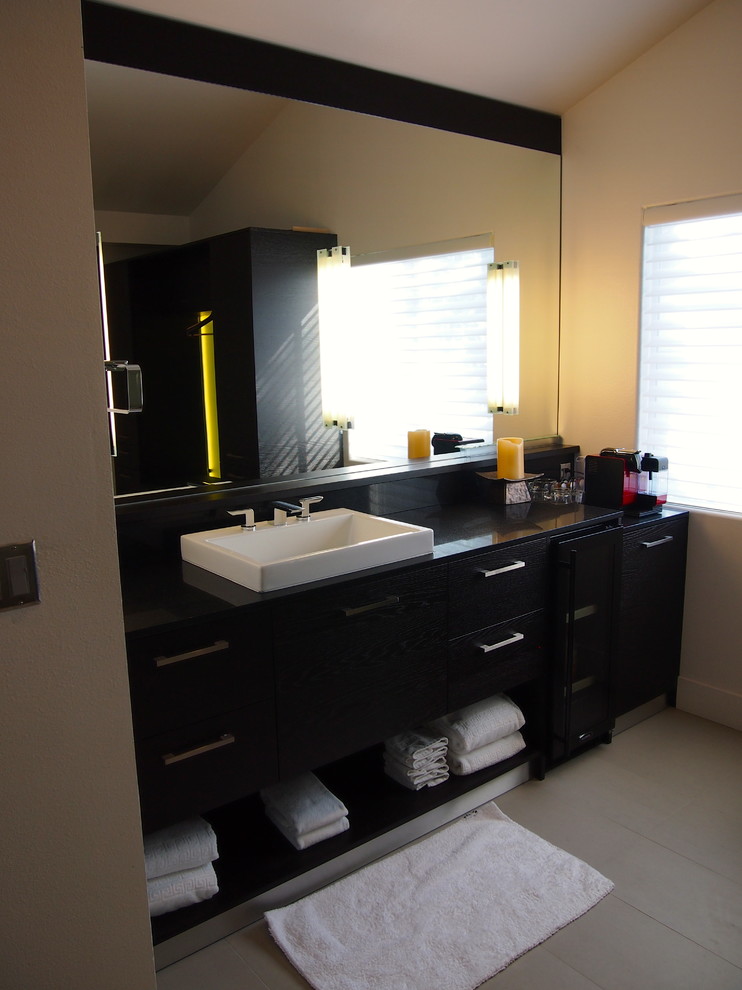 This is an example of a large modern ensuite wet room bathroom in Los Angeles with flat-panel cabinets, dark wood cabinets, a freestanding bath, a wall mounted toilet, beige tiles, beige walls, porcelain flooring, a submerged sink, engineered stone worktops, white floors, a hinged door, white worktops, double sinks, a floating vanity unit and a vaulted ceiling.