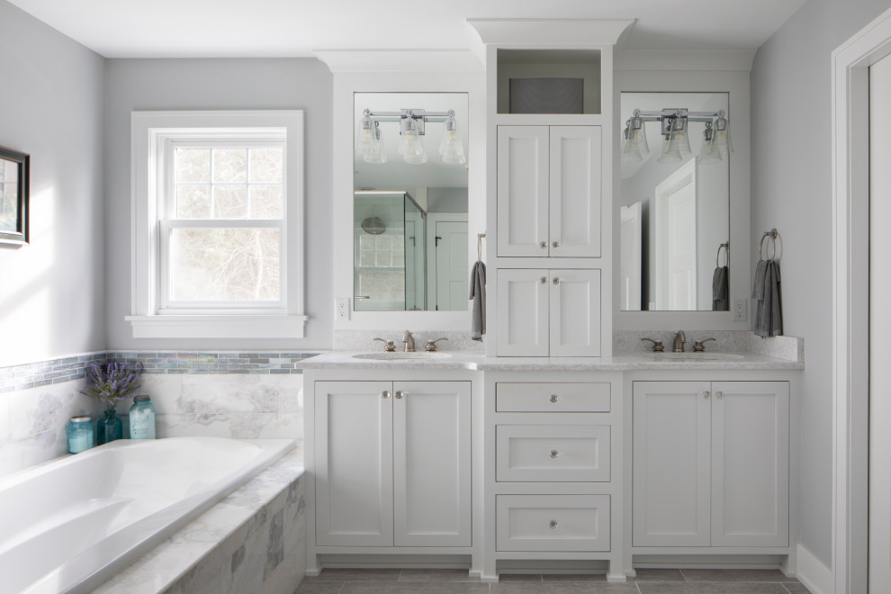 Amerikansk inredning av ett stort vit vitt en-suite badrum, med möbel-liknande, vita skåp, ett platsbyggt badkar, en dusch/badkar-kombination, flerfärgad kakel, glaskakel, grå väggar, cementgolv, ett undermonterad handfat, bänkskiva i kvarts, grått golv och dusch med gångjärnsdörr