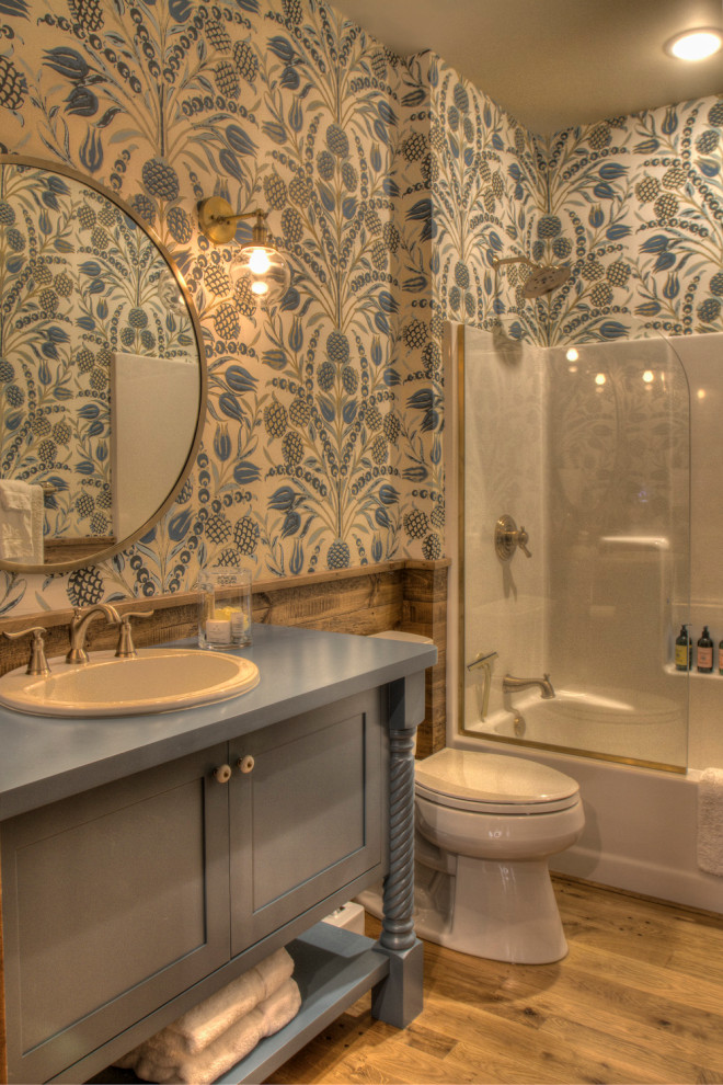 Example of a mid-sized danish master medium tone wood floor and brown floor bathroom design in Minneapolis with flat-panel cabinets, blue cabinets, a two-piece toilet, multicolored walls, a drop-in sink, wood countertops and blue countertops