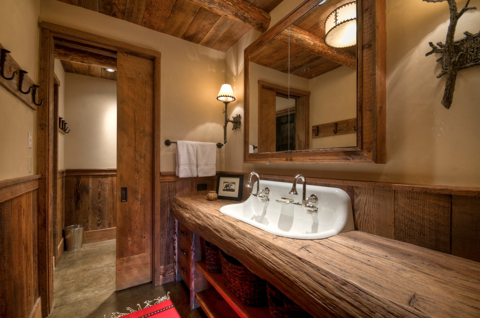 Example of a mid-sized mountain style 3/4 brown tile concrete floor bathroom design in Other with wood countertops, flat-panel cabinets, a two-piece toilet, beige walls, a drop-in sink, medium tone wood cabinets and brown countertops