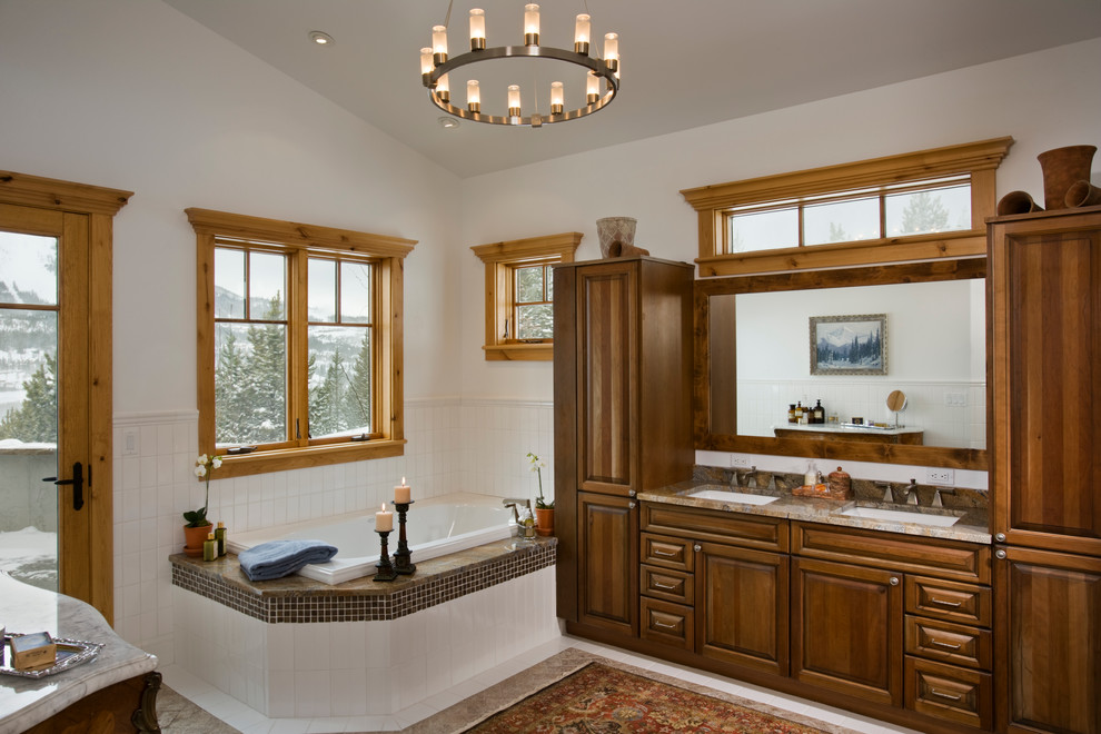 Large traditional ensuite bathroom in Other with raised-panel cabinets, medium wood cabinets, a corner bath, brown tiles, ceramic tiles, beige walls, travertine flooring, granite worktops and a submerged sink.