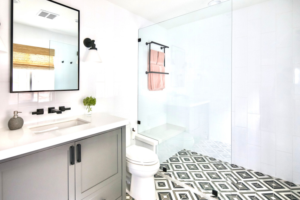 Aménagement d'une douche en alcôve classique avec un placard à porte shaker, des portes de placard grises, un carrelage blanc, un lavabo encastré, un sol multicolore, un plan de toilette blanc et meuble simple vasque.