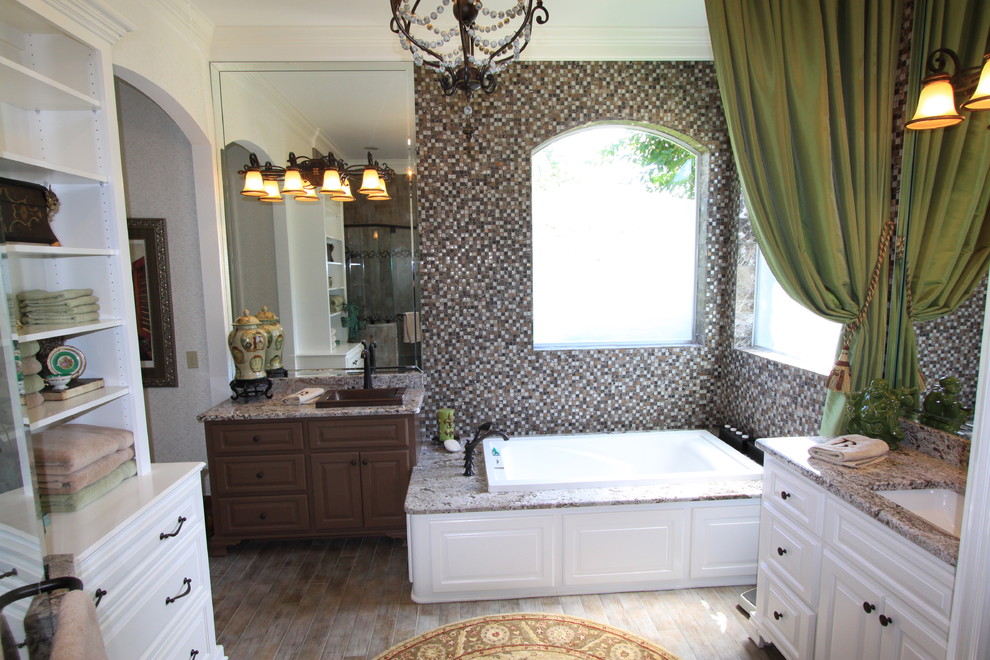 Klassisk inredning av ett stort en-suite badrum, med luckor med upphöjd panel, vita skåp, ett platsbyggt badkar, en toalettstol med hel cisternkåpa, ljust trägolv, brunt golv, en hörndusch, brun kakel, ett undermonterad handfat, granitbänkskiva och dusch med gångjärnsdörr