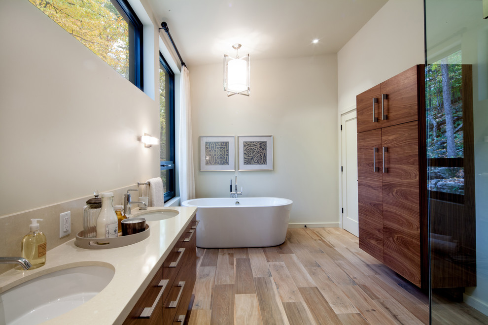 Cette photo montre une salle de bain principale tendance de taille moyenne avec une baignoire indépendante, un mur blanc, parquet clair, un lavabo posé et un sol marron.