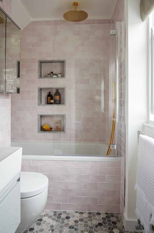 Design ideas for a small traditional grey and pink bathroom in London with flat-panel cabinets, a built-in bath, a shower/bath combination, pink tiles, white walls, ceramic flooring, grey cabinets, metro tiles, multi-coloured floors and white worktops.