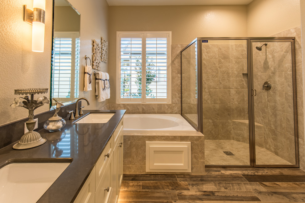 Photo of a country ensuite bathroom in Sacramento with recessed-panel cabinets, white cabinets, a built-in bath, a shower/bath combination, beige tiles, porcelain tiles, a submerged sink, quartz worktops and a hinged door.