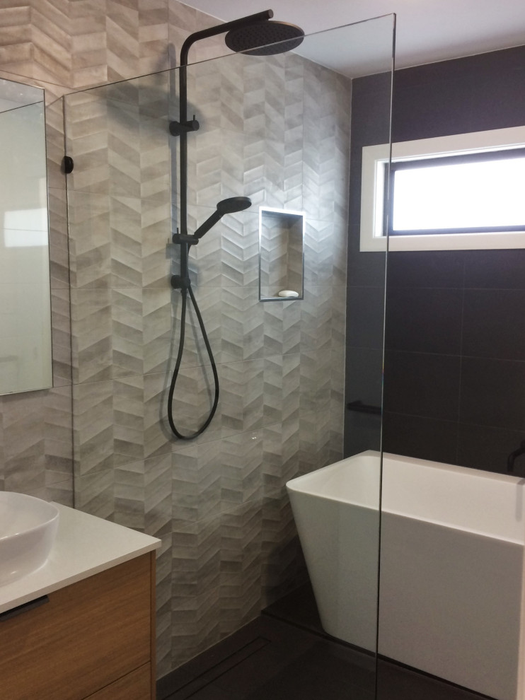 Photo of a medium sized contemporary family bathroom in Brisbane with flat-panel cabinets, medium wood cabinets, a freestanding bath, a walk-in shower, multi-coloured tiles, ceramic tiles, black walls, ceramic flooring, a vessel sink, engineered stone worktops, black floors, an open shower, white worktops, a wall niche, double sinks and a floating vanity unit.