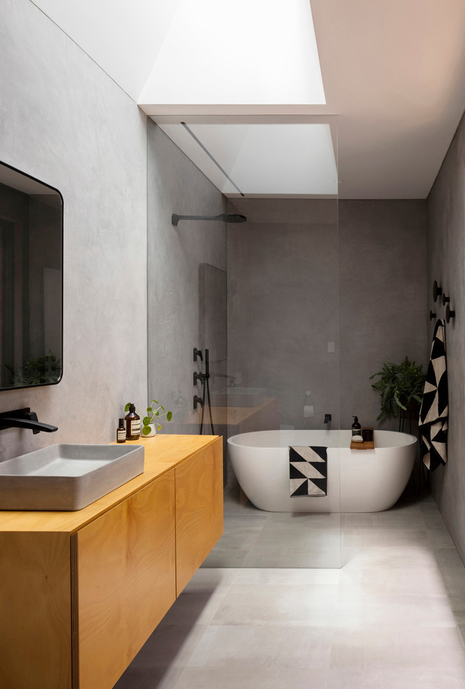 Идея дизайна: главная ванная комната в стиле модернизм с плоскими фасадами, фасадами цвета дерева среднего тона, отдельно стоящей ванной, душевой комнатой, серой плиткой, серыми стенами, настольной раковиной, столешницей из дерева, серым полом, открытым душем и коричневой столешницей