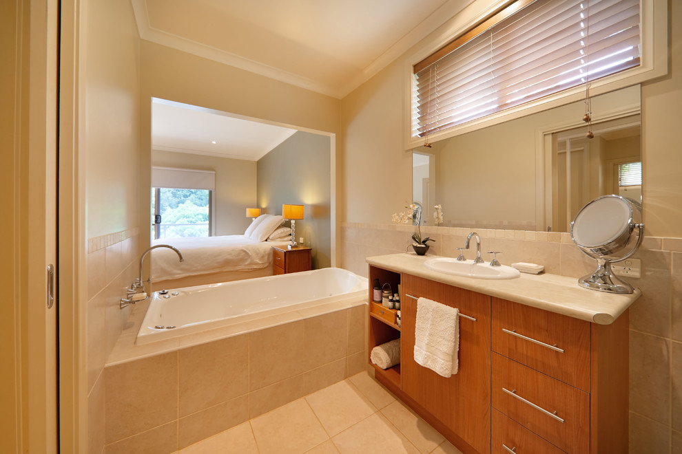 シドニーにあるコンテンポラリースタイルのおしゃれな浴室 (オーバーカウンターシンク、フラットパネル扉のキャビネット、中間色木目調キャビネット、ドロップイン型浴槽、ベージュのタイル) の写真