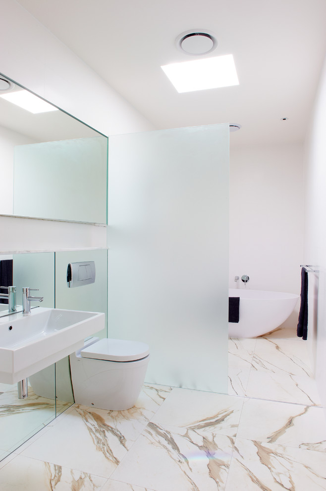Идея дизайна: большая главная ванная комната в современном стиле с подвесной раковиной, мраморной столешницей, отдельно стоящей ванной, двойным душем, инсталляцией, белой плиткой, плиткой из листового камня, белыми стенами и мраморным полом