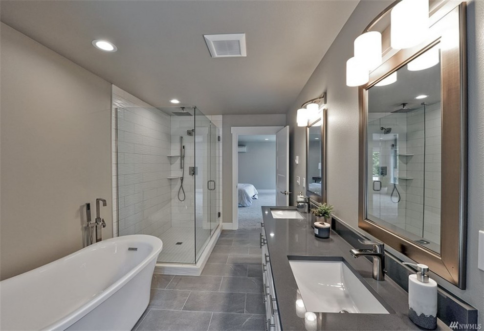 This is an example of a medium sized contemporary ensuite bathroom in Seattle with shaker cabinets, white cabinets, a freestanding bath, a corner shower, a one-piece toilet, metro tiles, grey walls, porcelain flooring, a submerged sink, quartz worktops, grey floors, a hinged door and grey worktops.