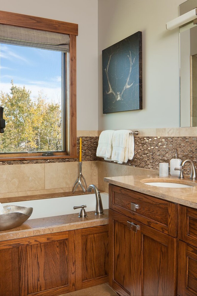 Inspiration pour une salle de bain principale traditionnelle en bois brun de taille moyenne avec un carrelage beige, des carreaux en allumettes, un mur blanc, une baignoire encastrée, un lavabo encastré, un placard à porte shaker et un sol en travertin.