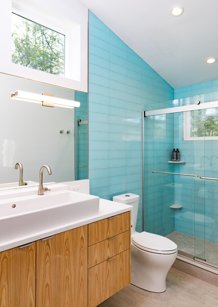 На фото: ванная комната в современном стиле с плоскими фасадами, фасадами цвета дерева среднего тона, душем в нише, синей плиткой, стеклянной плиткой, белыми стенами, душевой кабиной, раковиной с несколькими смесителями, столешницей из искусственного кварца, бежевым полом и душем с раздвижными дверями с