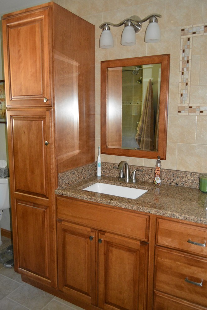 Klassisk inredning av ett mellanstort en-suite badrum, med ett undermonterad handfat, luckor med upphöjd panel, skåp i mellenmörkt trä, bänkskiva i kvarts, beige kakel och beige väggar