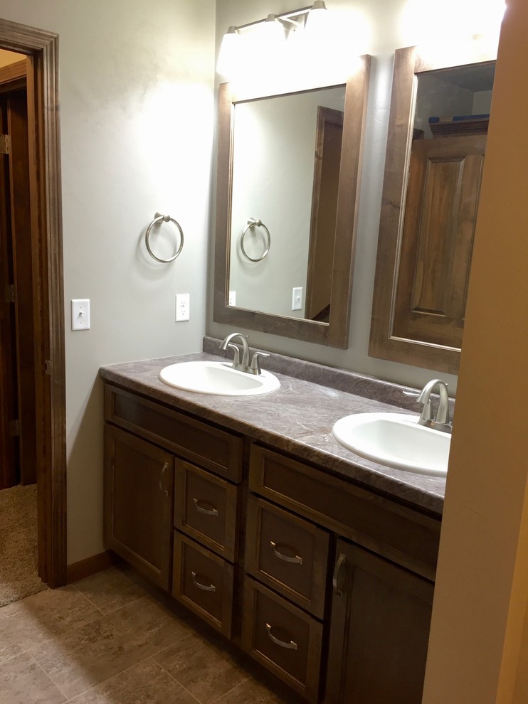 На фото: главная ванная комната в стиле кантри с фасадами цвета дерева среднего тона, душем над ванной, разноцветной плиткой, керамической плиткой, серыми стенами, полом из керамической плитки и столешницей из ламината