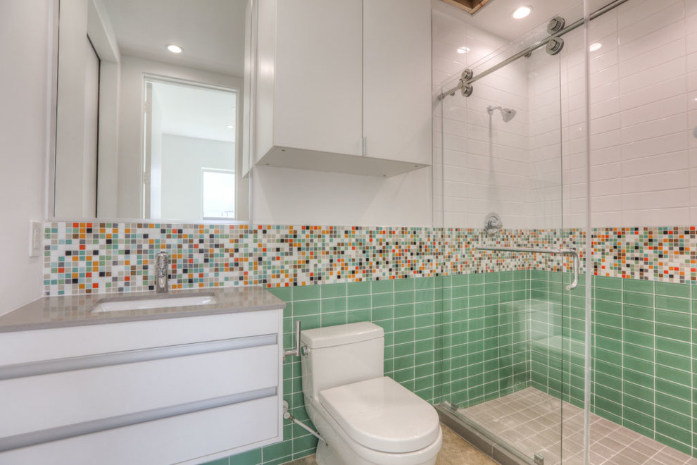 This is an example of a small modern shower room bathroom in Houston with flat-panel cabinets, white cabinets, an alcove shower, a one-piece toilet, multi-coloured tiles, mosaic tiles, white walls, travertine flooring, a submerged sink, solid surface worktops, beige floors and a sliding door.