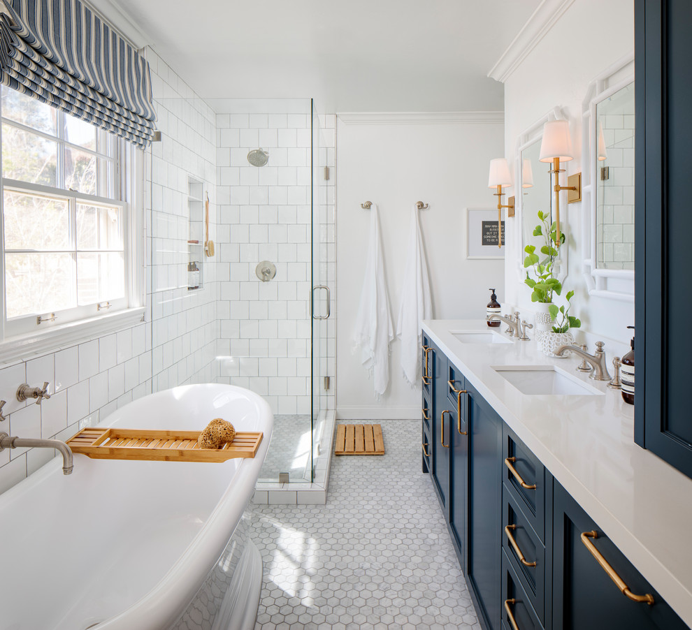 Inspiration pour une salle de bain principale marine de taille moyenne avec un placard à porte shaker, des portes de placard bleues, une baignoire indépendante, une douche d'angle, un carrelage blanc, des carreaux de céramique, un mur blanc, un sol en marbre, un lavabo encastré, un plan de toilette en quartz modifié, un sol gris, une cabine de douche à porte battante, un plan de toilette blanc, une niche et meuble double vasque.