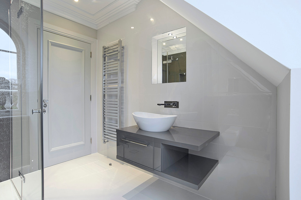 Cette image montre une salle d'eau design de taille moyenne avec un plan vasque, des portes de placard grises, une douche d'angle, un carrelage beige et un mur beige.