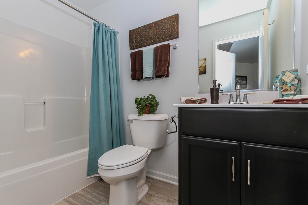 Small traditional family bathroom in Chicago with flat-panel cabinets, dark wood cabinets, a shower/bath combination, a two-piece toilet, white walls, ceramic flooring, an integrated sink, solid surface worktops, beige floors and a shower curtain.